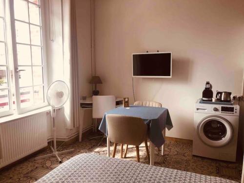 une chambre avec une table et un lave-linge dans l'établissement Studio Le Mansart au pied du Château Insead, à Fontainebleau