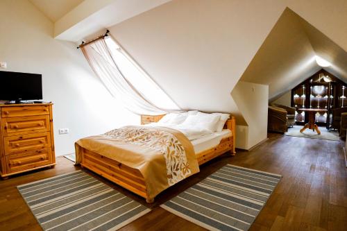 a bedroom with a bed and a dresser and a television at Sasréti Vadászkastély Almamellék in Almamellék