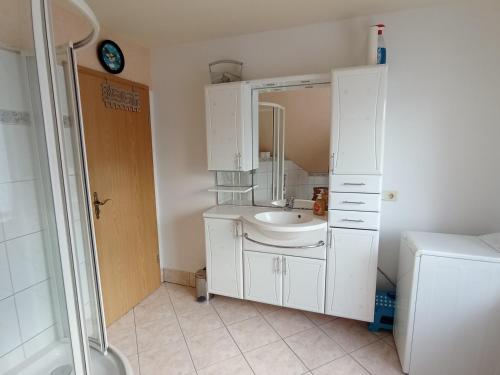 a white bathroom with a sink and a mirror at Ferienhaus Juleta in Briesen