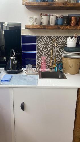 a kitchen counter with a sink and some dishes at Studio with a hot tub and garden in East Barnet