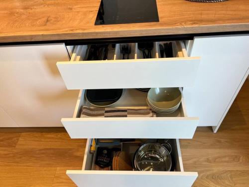 an open drawer in a kitchen cabinet with dishes at Nice apartment with a balcony by the sea. in Ķesterciems