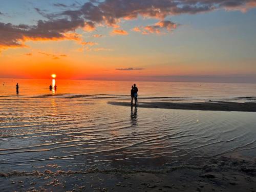 a person standing on the beach watching the sunset at Nice apartment with a balcony by the sea. in Ķesterciems