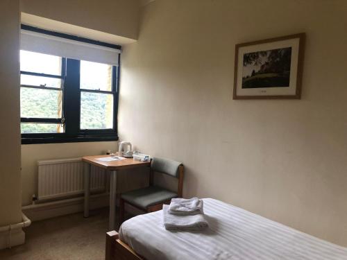 a bedroom with a bed and a table and a chair at Plas Tan y Bwlch in Maentwrog