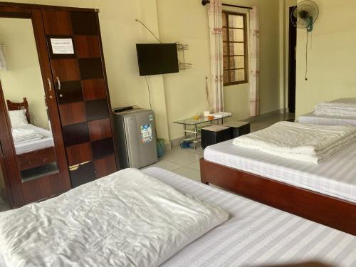 a hotel room with two beds and a television at Khách Sạn Minh Nghĩa Trung Tâm Đà Lạt - 밍냐 저럄한 호텔 in Da Lat