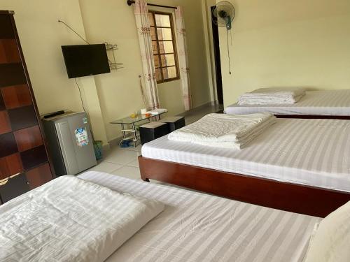 a room with two beds and a television in it at Khách Sạn Minh Nghĩa Trung Tâm Đà Lạt - 밍냐 저럄한 호텔 in Da Lat