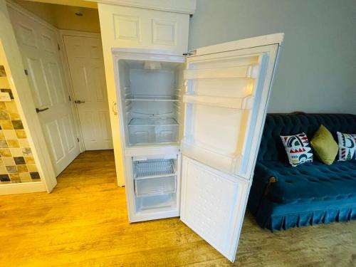um frigorífico com a porta aberta ao lado de um sofá em Cosy ground floor apartment em Huntingdon