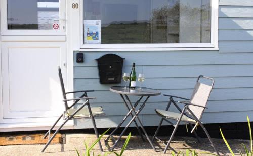 a table with two chairs and a table with wine bottles at Chalet 80 in Sandown