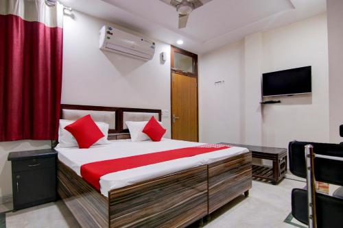 1 dormitorio con 1 cama con almohadas rojas y TV en Flagship Shyam Villa en Nueva Delhi