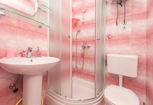 un bagno rosa con lavandino e doccia di Apartments Vanesa a Dugi Rat (Punta Lunga)