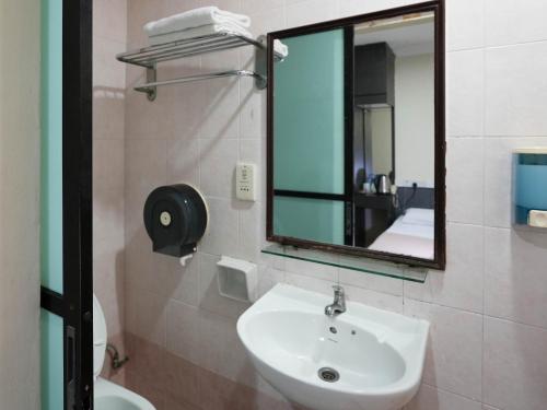 a bathroom with a sink and a mirror and a toilet at Amrise Hotel, Check in at 10PM, Check out at 9AM in Singapore