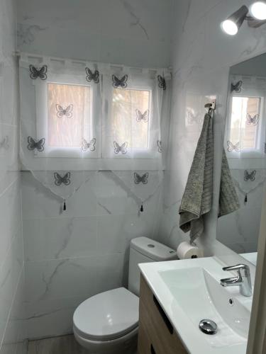 y baño con aseo, lavabo y mariposas en la pared. en Habitación Amaya 1, en Las Corts