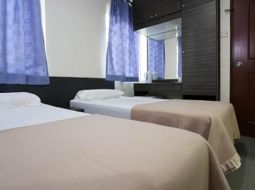 a bedroom with two beds and a window with blue curtains at Amrise Hotel, Check in at 10PM, Check out at 9AM in Singapore