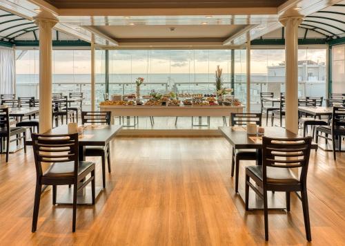 um restaurante com mesas e cadeiras e vista para o oceano em Hotel Augustus em Rimini