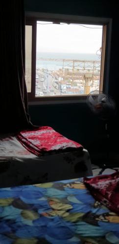 um quarto com uma janela e uma cama com um cobertor em الاسكندريه em Alexandria