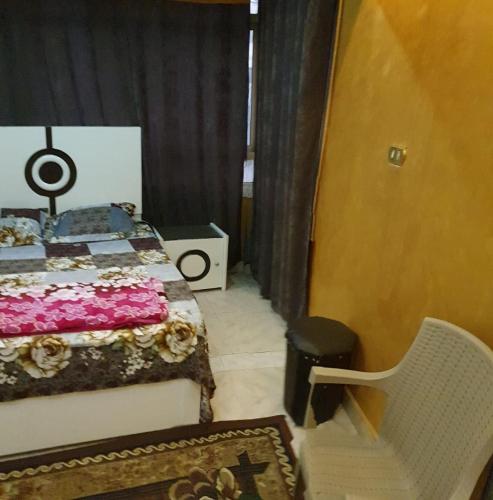 een slaapkamer met een bed, een stoel en een tapijt bij الاسكندريه in Alexandrië