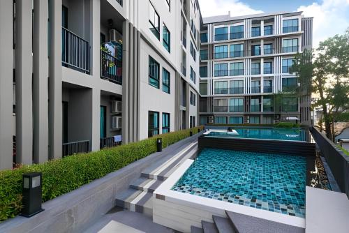 a swimming pool in front of a building at Bangtao - Laguna center, 1BR, Near Laguna Center in Ban Thalat Choeng Thale