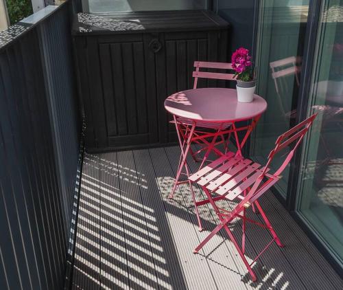 - Balcón con mesa rosa y 2 sillas en Cool Dalston studio with balcony and gym, en Londres