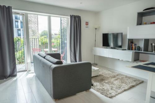 uma sala de estar com um sofá e uma televisão em Cool Dalston studio with balcony and gym em Londres