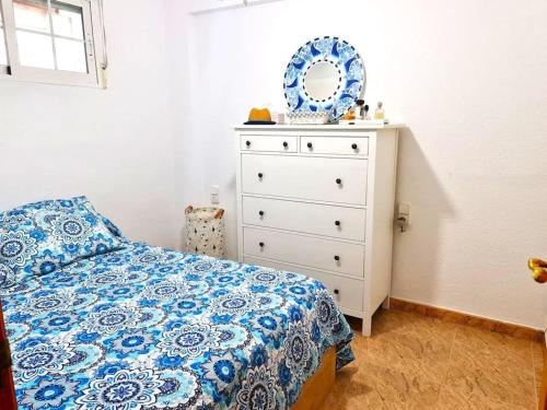 a bedroom with a bed and a dresser with a mirror at Bonito apartamento con vistas al mar in Playa Pobla de Farnals