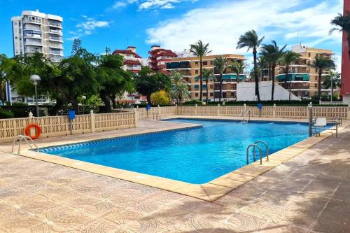 a large swimming pool in a city with buildings at Bonito apartamento con vistas al mar in Playa Pobla de Farnals