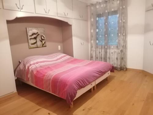 - une chambre avec un lit rose et une fenêtre dans l'établissement Appartement au calme près du lac d'Annecy, à Saint-Jorioz