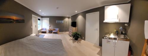 Il comprend une chambre avec un lit et une cuisine avec un évier. dans l'établissement Stilren suite med egen inngang og kokemuligheter., à Tromsø
