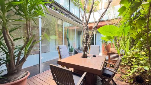 einen Holztisch und Stühle auf einer Terrasse mit Pflanzen in der Unterkunft ArtlifeBCN Urban Oasis Apartment in Barcelona