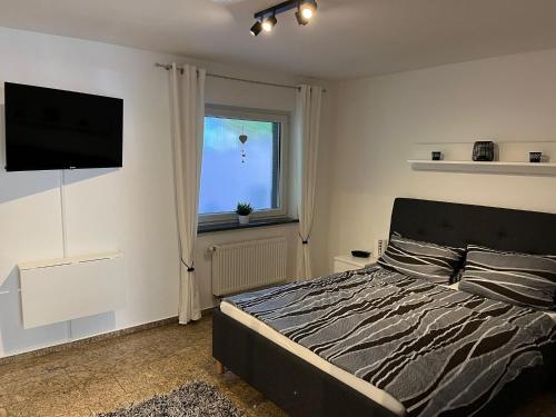 Un dormitorio con una cama y un televisor de pantalla plana. en Ferienwohnung Mara, en Ettringen