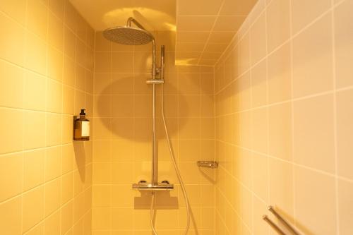 een douche in een badkamer met gele tegels bij hotel calisto in Amsterdam