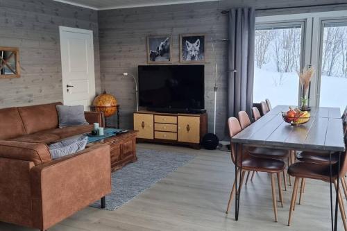 a living room with a couch and a table and a television at Hele utleiebolig Årøybuktneset in Lyngseidet