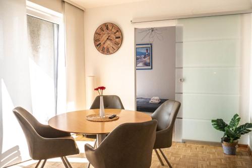 une salle à manger avec une table, des chaises et une horloge dans l'établissement Modern, fully equipped apartment, ideal for Messe fair, à Hanovre