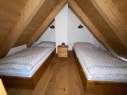 two beds in a attic room with wooden floors at Roubenka svatý Vít in Važice