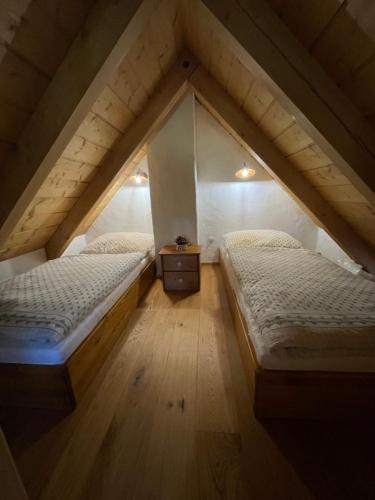 a attic room with two beds and a wooden floor at Roubenka svatý Vít in Važice