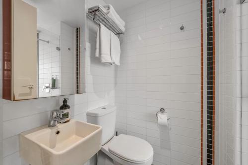 a white bathroom with a toilet and a sink at City Stays in Melbourne