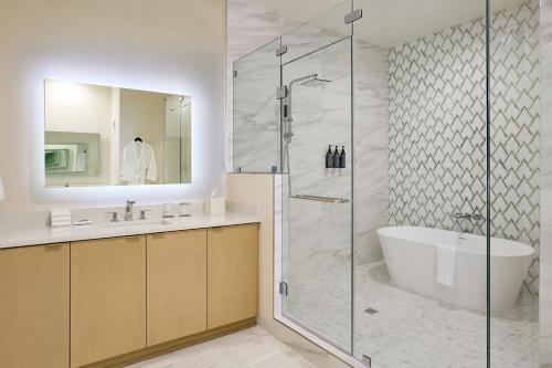 a bathroom with a shower and a tub and a sink at The Westin Raleigh-Durham Airport in Raleigh