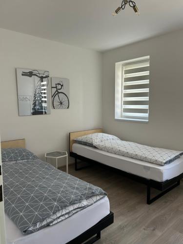 a bedroom with two beds and a window with a bike on the wall at Penzion NoFasada in Bzenec