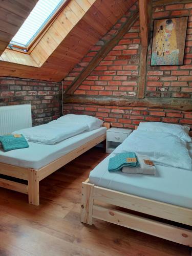 two beds in a room with a brick wall at Dom Gościnny Magiczna Stodółka in Osiecznica