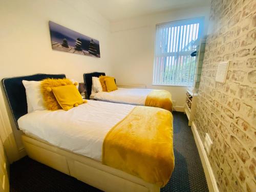 a bedroom with two beds with yellow pillows at Contractor Flat in Town Sleep 4 with yard in Birkenhead