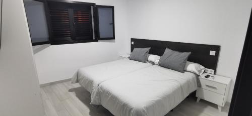 Carrizal的住宿－Situación inmejorable. Céntrico y tranquilo，一间卧室配有一张白色的床和黑色床头板
