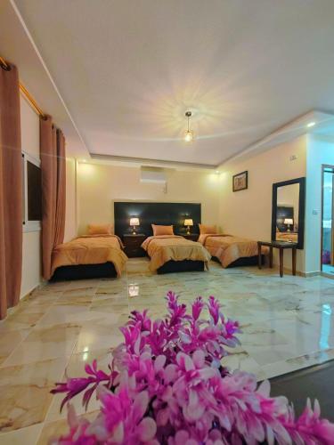 a hotel room with two beds and purple flowers at iHome Petra in Wadi Musa