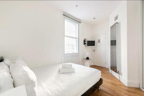 Lovely one bedroom in the heart of London في لندن: غرفة نوم بيضاء مع سرير أبيض كبير ونافذة