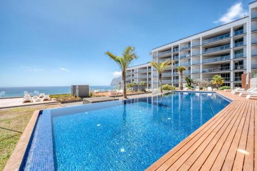 a swimming pool in front of a building with the ocean at Suite BM - 3 Pools-Gym-AC-Huge Balcony Sea View in Funchal