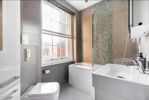 a bathroom with a sink and a toilet and a window at stylish flat in heart of London in London