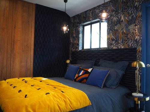 a bedroom with a large bed with a yellow blanket at Maison en centre ville avec extérieur in Compiègne