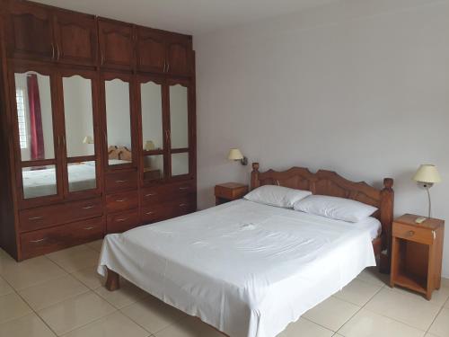 1 dormitorio con 1 cama y un gran armario de madera en Palmont Commercial Self-Catering Apartments - Beau Vallon, en Beau Vallon
