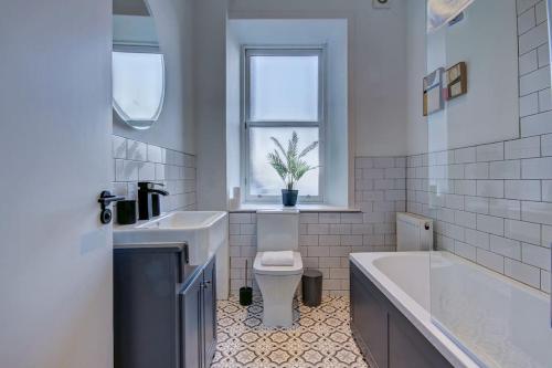 a bathroom with a tub and a toilet and a sink at The Annick - Coorie Doon Apartments in Irvine