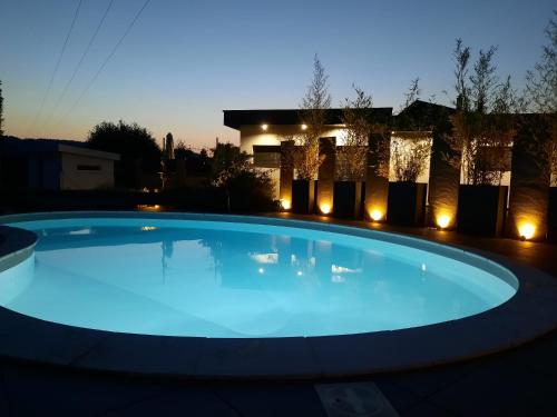 勒蒂約的住宿－GITE DE LA PIERRE PLATE，夜晚在房子前面有一个蓝色的大游泳池