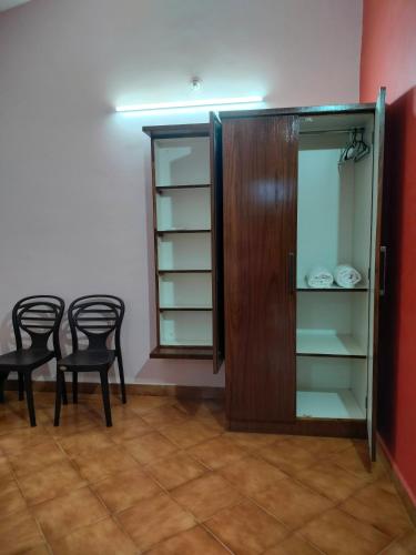 a room with two chairs and a cabinet with shelves at Villa Cleto Guest House in Panaji