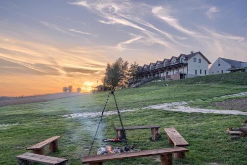 a picnic table with a fire in a field at Azyl Widoki in Wielkie Leżno