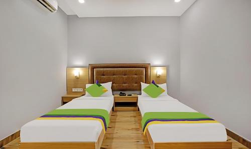 ムンバイにあるZARA GRAND HOTELの白い壁とウッドフロアの客室で、ベッド2台が備わります。